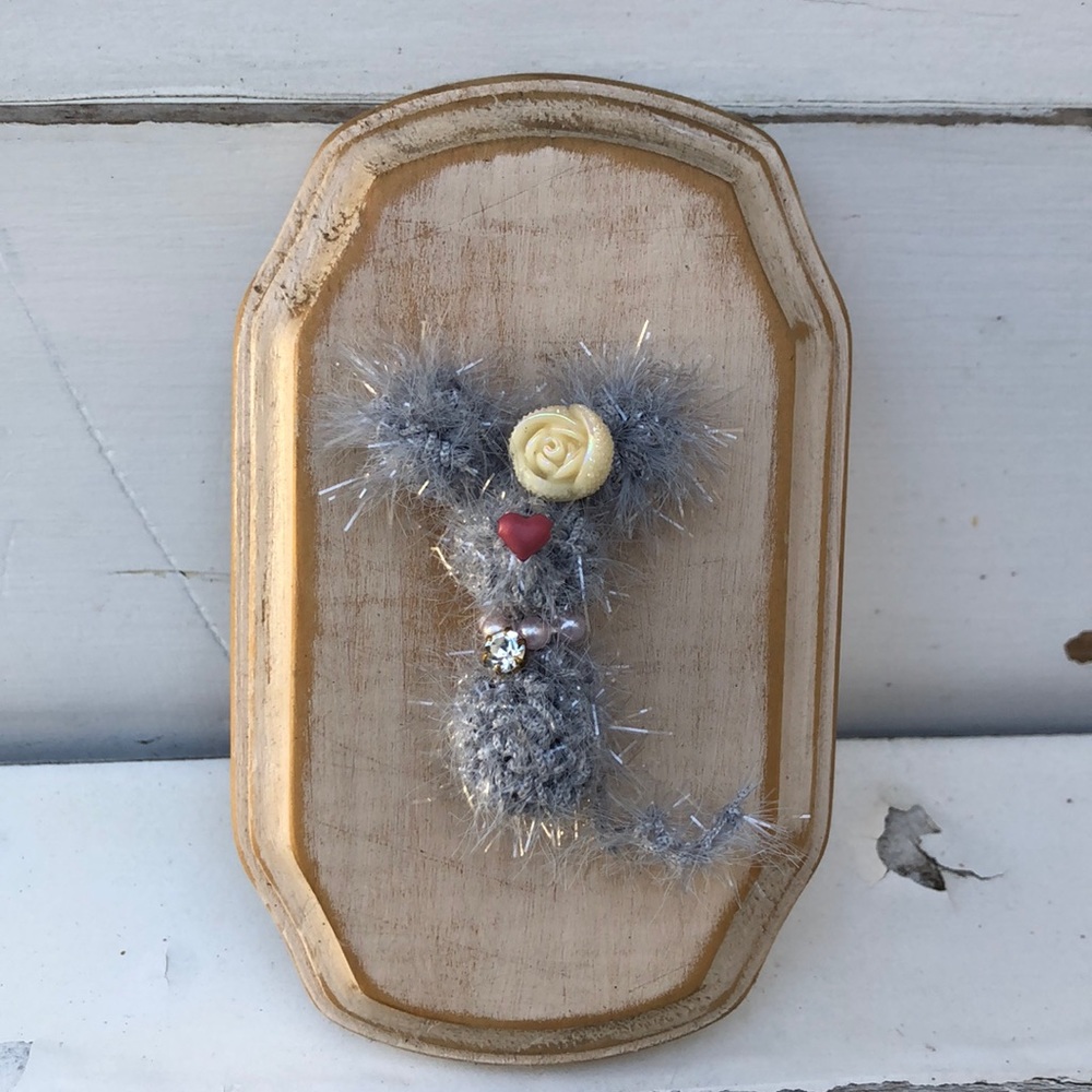 Crocheted tiny mouse on a wood plaque